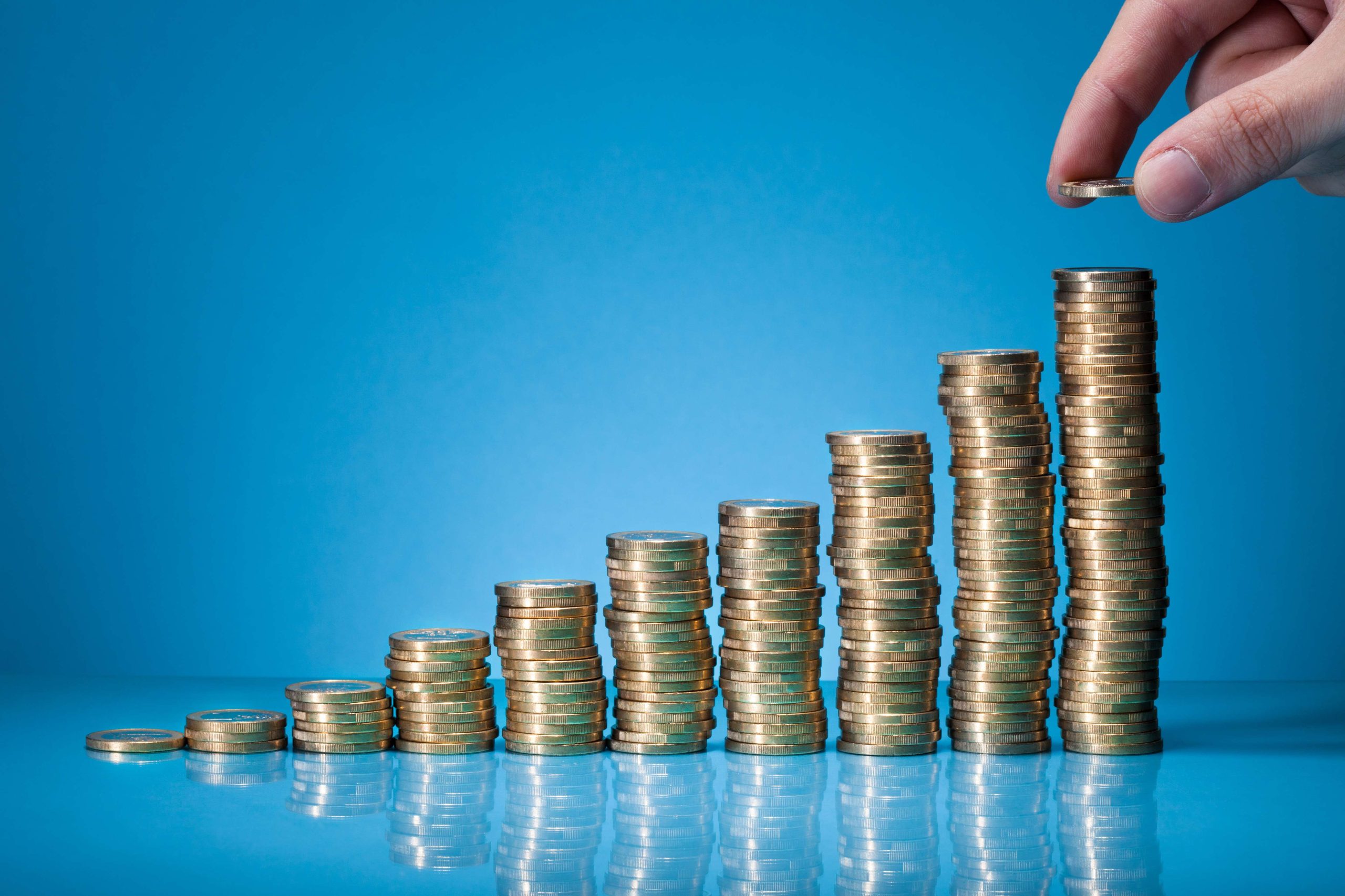 Hand Placing Coin On Stack Of Coins
