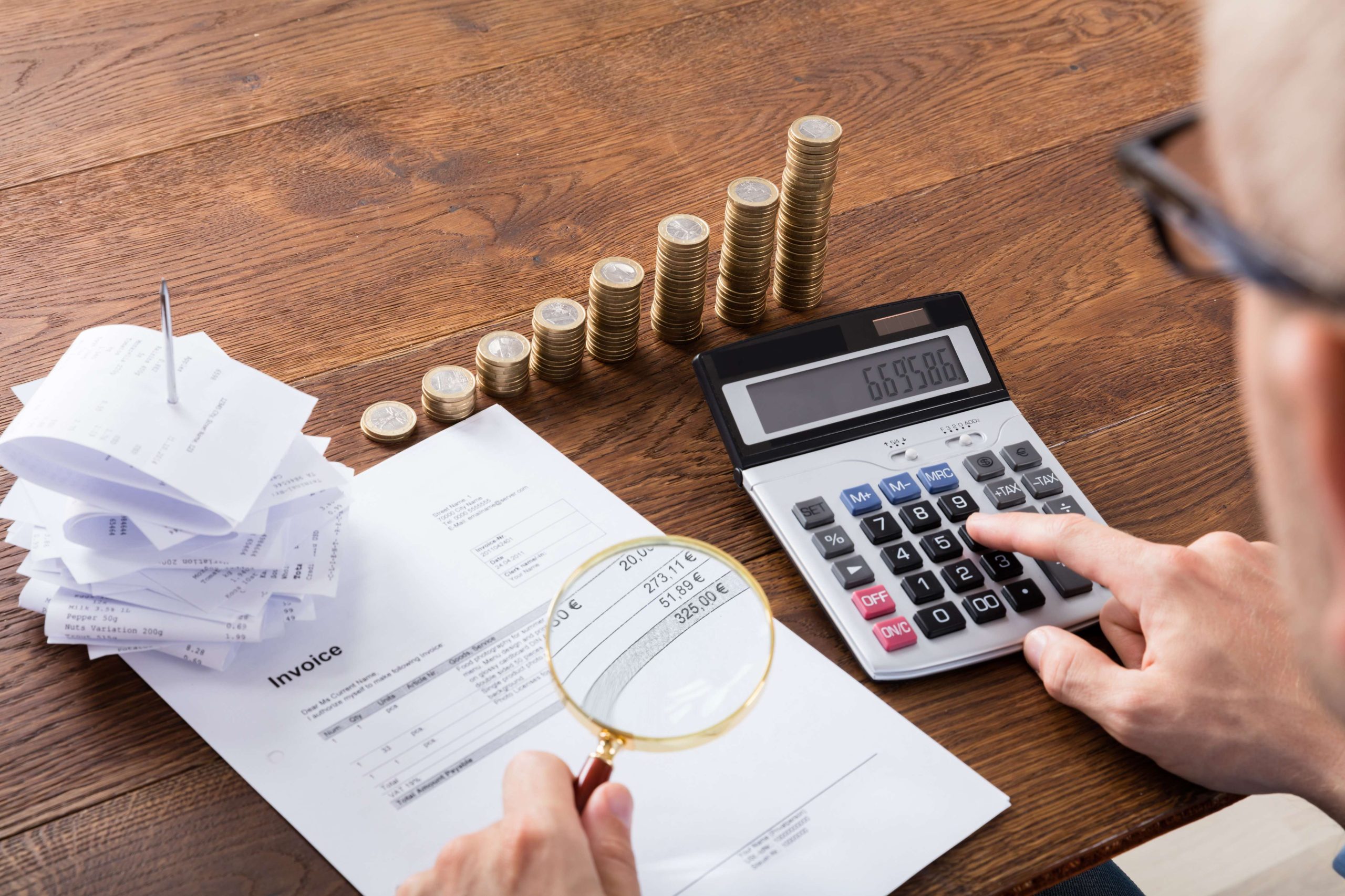 Person Calculating Invoice On Desk