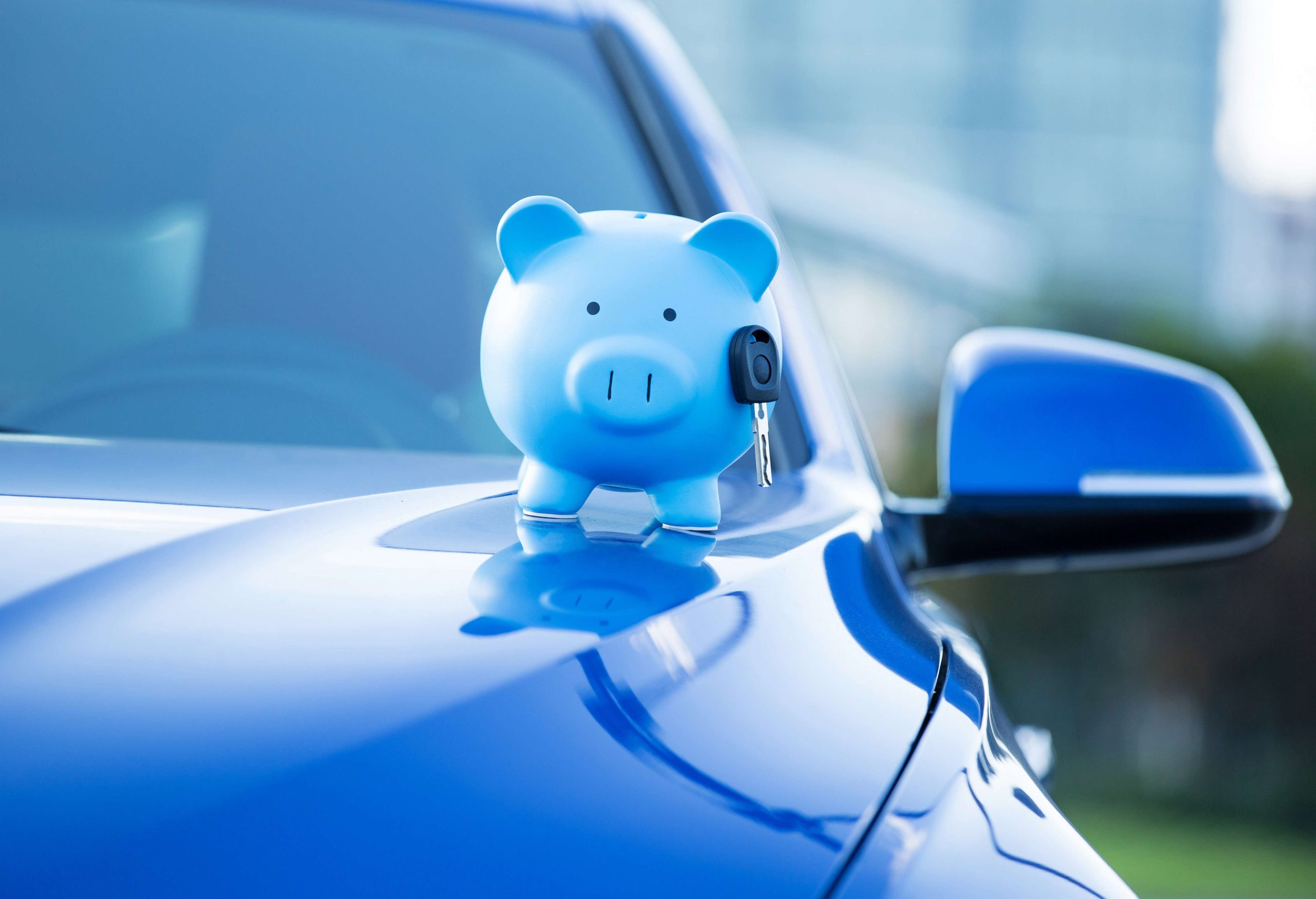 Piggy bank and key on a car hood