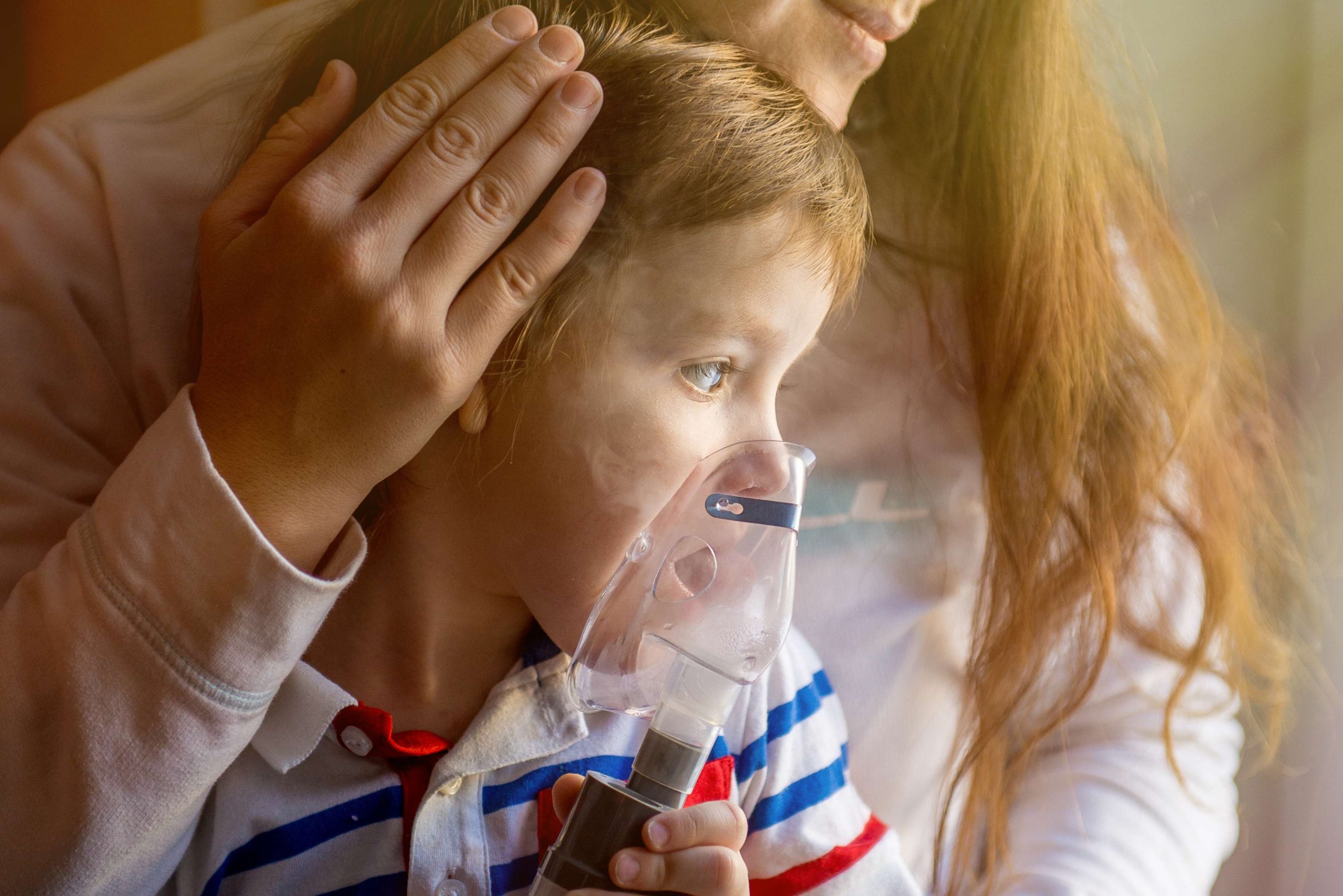 Young woman with son doing inhalation  a nebulizer at home
